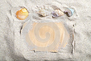 Gray blank paper covered with sand and seashells. A letter stacked on the beach