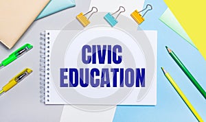 On a gray and blue background are stationery of yellow-green color, a notebook with the text CIVIC EDUCATION. Flat lay
