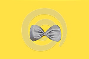 A gray bow tie on a yellow background