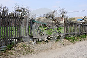 Gray broken wooden plank fence in green grass on a rural street