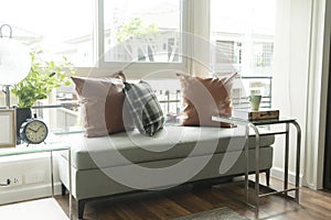 Gray and brown pillows over sofa and window.