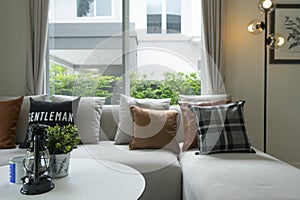 Gray and brown pillows over sofa and window.
