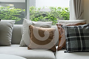 Gray and brown pillows over sofa and window.