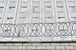 Gray building is fenced with barbed wire. Symbol of dictatorial and authoritarian regime.