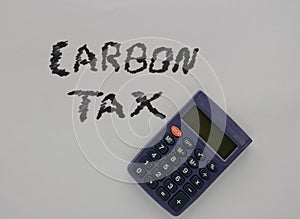 A gray calculator on top of a white sheet of paper that says, carbon tax