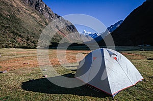 gray camping tent with high snowy mountains in the background, on the trekking of the quebrada santa cruz