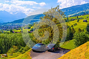 Gray car and brocken car on the road near wooden cottage houses on green fields, Grabs, Werdenberg, St. Gallen Switzerland