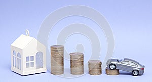 Gray car model and home with coins in the form of a histogram on a purple background. Concept of lending, savings, sale, lease of