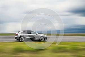 Gray car in motion, speed blurred background, side view of moving car with free space for text