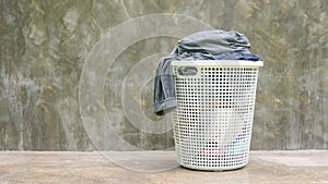 Gray clothes in a white hamper on a cement background
