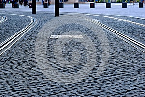 gray cobblestone cube granite pavement. rectangular shaped loosely set stones. steel tram rails embedded