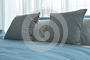 Gray color pillows on bed with blue blanket in modern bedroom interior