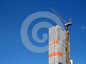 gray construction canvas sheet covered apartment building structure for safety with tower crane working on rooftop