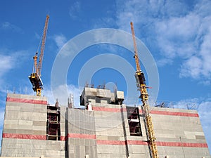 gray construction canvas sheet covered building structure for safety with two tower crane working on rooftop