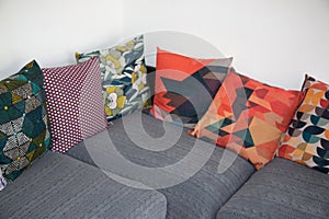 Gray corner sofa with several colorful cushions in interior house