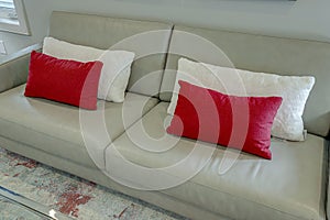 A gray couch with two red pillows and two white pillows
