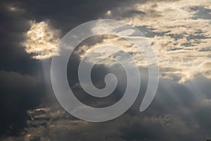 Gray Cumulus clouds in a blue sky with rays of the sun