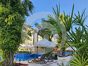 Gray deck chairs with an orange cushion by the pool with white umbrellas from the sun