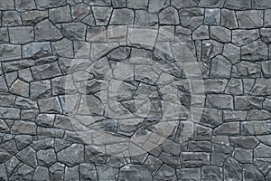Gray dirty stone wall. Texture of grey granite. Dark rough rocks background. Weathered dark gray grunge building`s facade. Stone