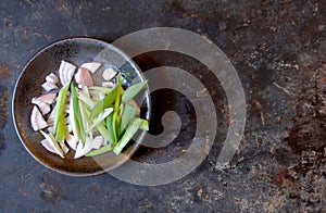 Gray dish of sliced shallots and scallions, left of cenger, on a multicolor gray background