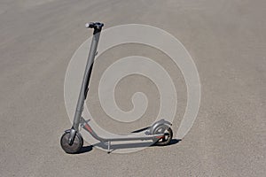 Gray electric stand-up scooter on tarmac asphalt road