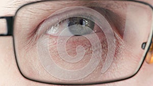 gray eye of middle-age caucasian male putting on and off diopter correction glasses, brightly lit closeup