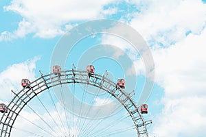 Gray ferris wheel with red booths against a blue sky