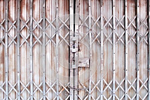 Gray folding steel door in interlace patterns for background and three rusty old locked