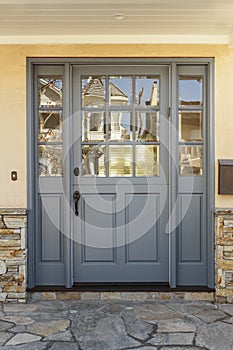 Gray front door to a home with shale porch