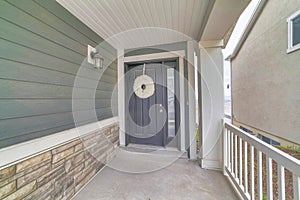 Gray front door with white holiday wreath and narrow sidelight at home facade
