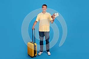 Gray globetrotter man with suitcase and tickets on blue background