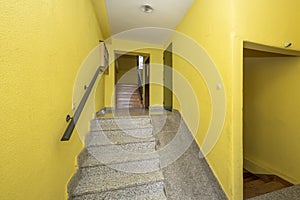 Gray granite stairs of a house with an unusable ramp due to its steepness and yellow walls