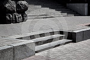 Gray granite steps in the middle of stone tile street pavement.