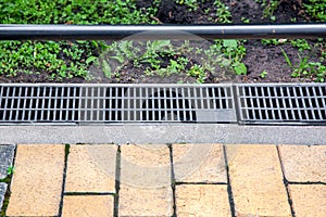 Gray grating of the drainage system for drainage of rainwater.