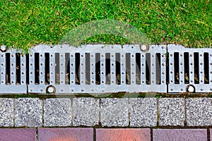 Gray grating of the drainage system for drainage of rainwater in the park.