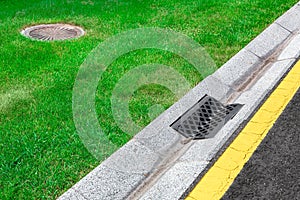 Gray gutter of a stormwater drainage system on the side of asphalt road.