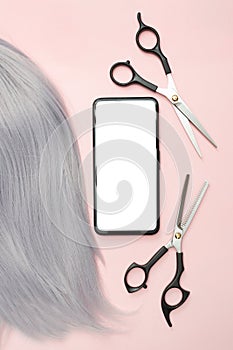 Gray hair and scissors for cutting. Creating beautiful hairstyles. Pink background. Top view. Flat lay. Copy space