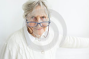 Gray hair senior lady in glasses on white wall background