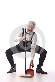 Gray-haired cleaner, janitor in a black jumpsuit with a mop and dustpan provides cleaning service, on white background