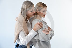 Gray-haired good-looking woman hugging her daughter with tenderness