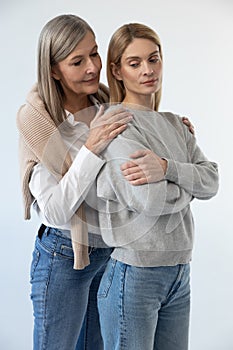 Gray-haired good-looking woman hugging her daughter with tenderness