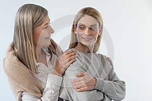 Gray-haired good-looking woman hugging her daughter with tenderness