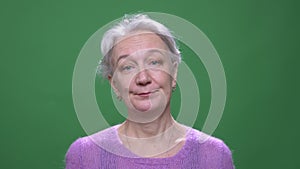 Gray haired grandmother turns head negatively to disagree isolated on green chromakey background.