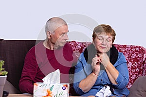 Gray-haired man caring for sick spouse at home. Woman having cold and sore throat from air conditioner, box of napkins