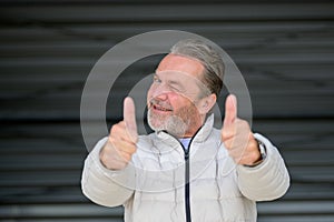 Gray haired man giving a thumbs up gesture and winks to the camera