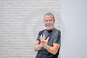 Gray haired man with a gray beard looking desperately to the camera