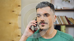 Gray-haired man talking on cellphone at home, making appointment with friends