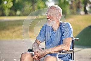 A gray-haired man in a wheel chair in the park