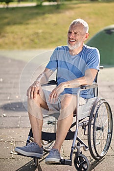 A gray-haired man in a wheel chair in the park