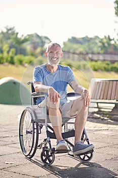 A gray-haired man in a wheel chair in the park